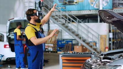 Qualified serviceman in auto repair shop using virtual reality goggles to visualize car components...
