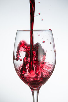 A glass of red wine is poured into a glass