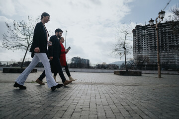 A group of colleagues engages in conversation while walking together on a city's promenade with construction in the background.