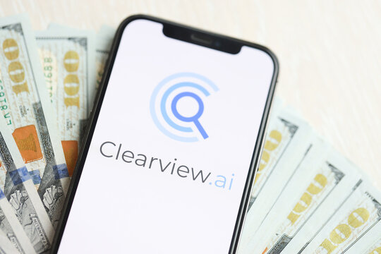 KYIV, UKRAINE - MARCH 17, 2024 ClearView logo on iPhone display screen with many hundred dollar bills. Artificial Intelligence engine