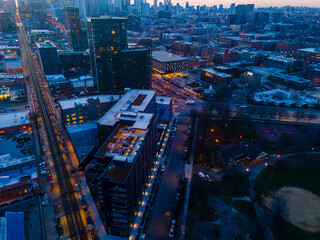 Fototapeta na wymiar A captivating aerial view of a cityscape at dusk, showcasing illuminated skyscrapers against the darkening sky. The golden hues of sunset paint a serene backdrop, highlighting architectural marvels