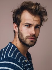 Obraz premium Men's hairstyles - Young Man with Windblown Hair and Striped Shirt Looking Off