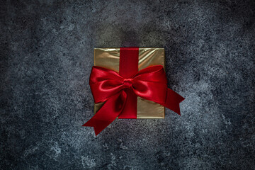 Golden Gift Box With Red Bow On Dark Background