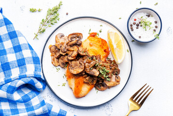 French breaded chicken breast steak with mushrooms and onion sauce with white wine and thyme on plate, white  table background, top view