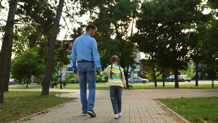 caring father walks with little child weekend park, child parent care, kid holds his father hand...