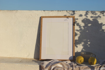 Vertical wooden frame picture mockup against white old textured white wall in sunlight. Fresh...