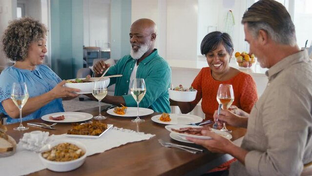 Group of mature friends at home relaxing meeting for lunch with wine - shot in slow motion