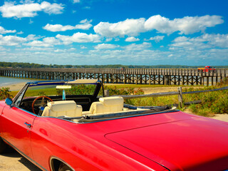Idyllic Retro-style Photo of Summer Beach Seascape with a convertible red antique car parked under...