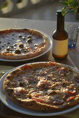 pizze servite al tavolo all'aperto in riva al mare con birre artigianali