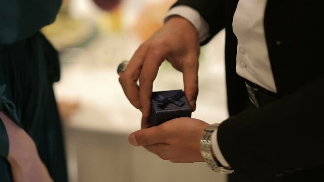 Man in a suit takes a case with a ring from his pocket and puts the ring on the finger of his beloved woman. Marriage proposal 