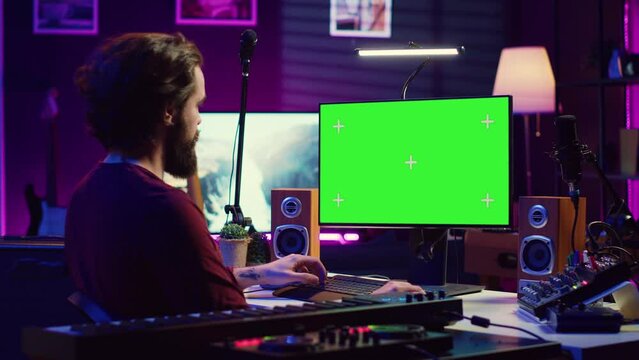 Sound engineer beginner learning acoustical engineering and mastering for music industry post production. Artist watches tutorial on greenscreen pc to use mixing console and equalizer. Camera A.