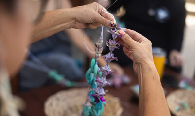 Close-up of a woman making lei in Hawaii, plumeria flowers garland crown handmade.