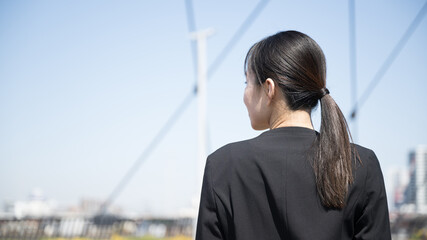 Woman in suit looking up at the sky in the city Faceless back view