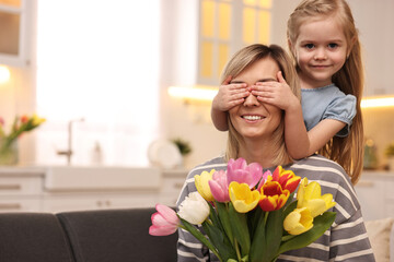 Obraz na płótnie Canvas Little girl surprising her mom with bouquet of tulips at home, space for text. Happy Mother`s Day