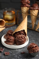 Tasty ice cream scoops, chocolate crumbs and waffle cones on dark textured table