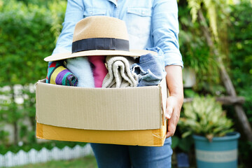 Volunteer collect cloth and hat in cardboard box to donate.