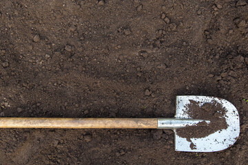 Brown dark soil ground texture background with copyspace and shovel top view. Organic farming, gardening, growing, agriculture concept