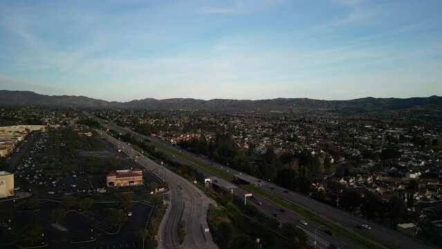 Aerial flying over Simi Valley California suburbs and shops at sunset on Highway 118