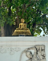 A golden Buddha statue, a serene religious monument in an Asian temple garden
