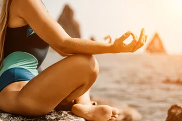 Fotobehang Yoga on the beach. A happy woman meditating in a yoga pose on the beach, surrounded by the ocean and rock mountains, promoting a healthy lifestyle outdoors in nature, and inspiring fitness concept. © svetograph