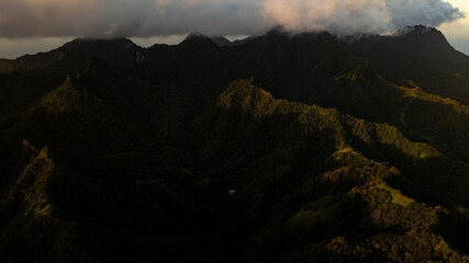 The setting sun touches a few ridges  while darkness slowly envelopes the rest of the Rarotonga's island mountain range.