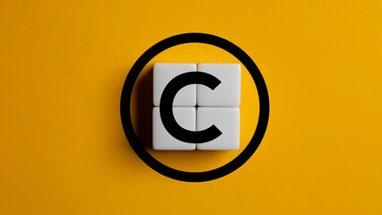 Copyright symbol on wooden blocks on yellow background. Concept of patenting or copyright...