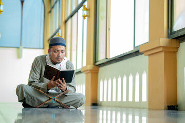 Ramadan, Quran, Islam,  An Asian Muslim man is sitting and reading the Quran. The peace in the...