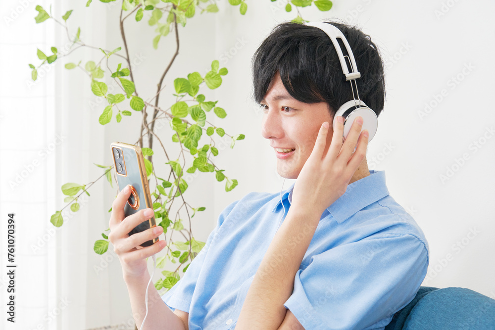 Poster リビングルームでスマホで音楽を聴く若い男性