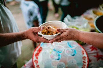The hand of the wanderer extends to receive food from donations. With volunteers scooping food: the idea of helping with hunger