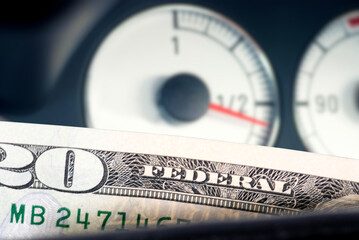 Dollar bills and fuel gauge in a car