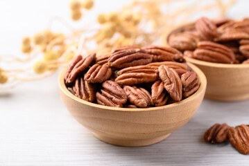Raw peeled pecan nuts in wooden bowl on white table, Food ingredient