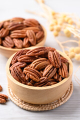 Raw peeled pecan nuts in wooden bowl on white table, Food ingredient
