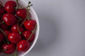 midsection of cherries in a bowl on isolated white background