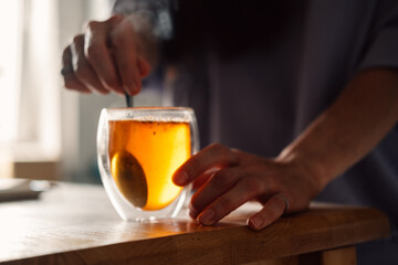 tranquil morning as woman carefully stirs tea, steam adding warmth to serene atmosphere of kitchen.