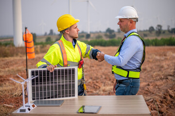 Engineers and manager wearing uniform holding solar call panel work cooperate hand teamwork in wind...