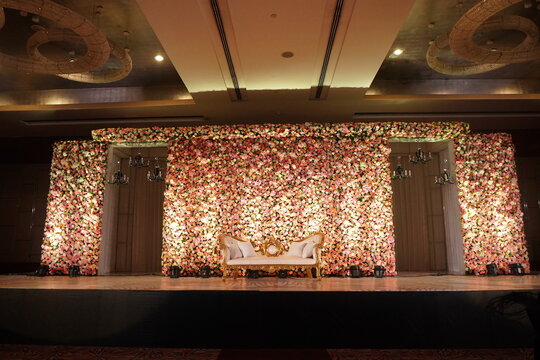 wedding backdrop. An elegantly staged traditional stage with flowers for the wedding couple to sit and receive blessings from the guests. Wedding venues and decorations for Indian wedding decors.