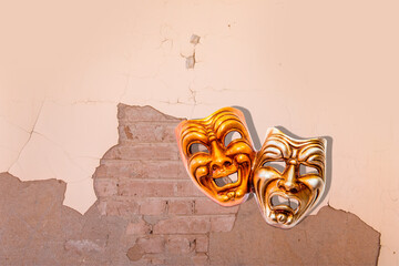 Comedy and Tragedy theater venetian mask hanging on a old shabby orange wall. Background, texture.Orange old paint on a rustic background 