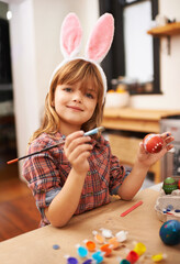 Happy girl, portrait and paint with easter egg for colorful art, tradition or holiday crafts at home. Young child enjoying color, activity or artwork with smile, paintbrush or bunny ears at the house