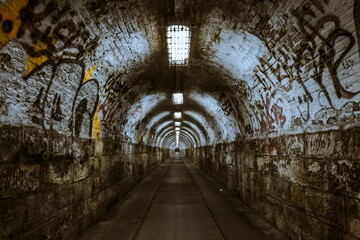The old arched tunnel is adorned with vibrant graffiti art, each colorful mural adding a sense of urban vibrancy and creativity to the weathered structure.