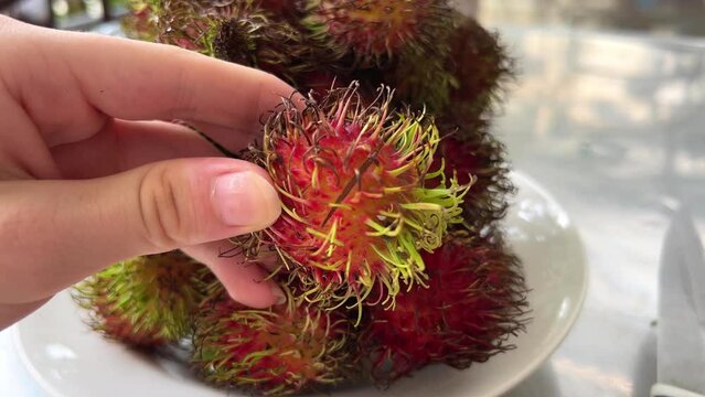 Fresh rambutan with green leaf on wooden background, relating view. High quality 4k footage
