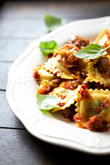 Ravioli with mushrooms and fresh basil. Dark wooden background. Close up	