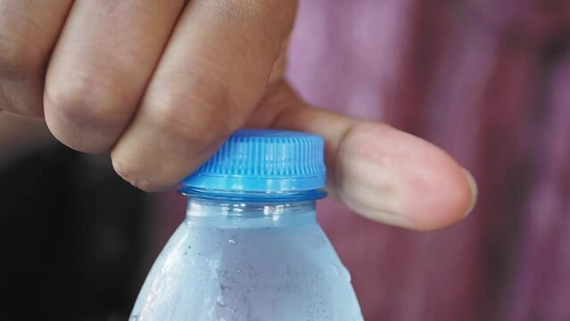 open a cap of a plastic water bottle 