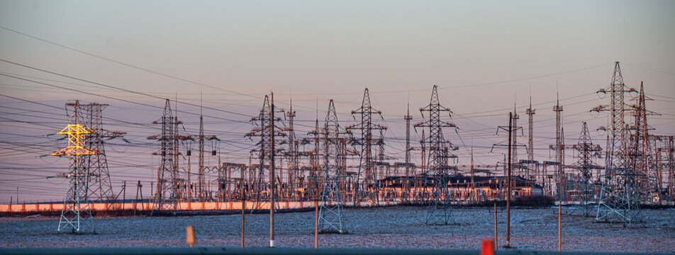 High-voltage direct current line Power lines at sunset, sun rays. High voltage tower against the sky. Energetics