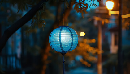 A blue lantern hangs from a tree in a city street