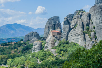 Fototapeta na wymiar A panoramic view of monastery set against a backdrop of rugged cliffs and vegetation, in Meteora, Greece