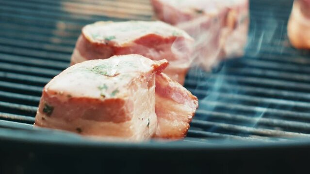 Cooking bacon wrapped pork tenderloin on a barbecue grill 