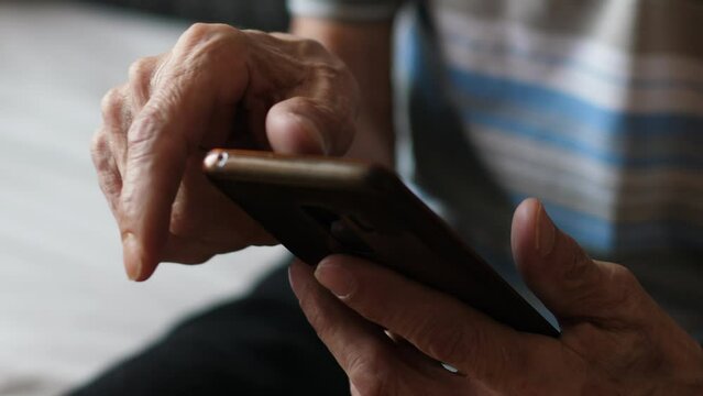 A pensioner and his mobile information feed. hands of an elderly man using a smartphone scrolling news and content on the gadget screen. activity in old age
