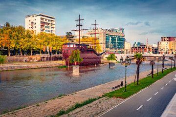 Spectacular spring cityscape of capital of North Macedonia - Skopje with old wooden sailboat and empty street at early morning. Traveling concept background. - obrazy, fototapety, plakaty