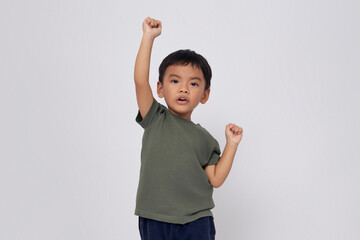 Excited 2-3 years old Asian boy wearing a green t-shirt looking at the camera while doing winner gesture isolated on white background