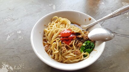 Stir-fried chinese noodles with chicken. Chicken noodle soup with noodles, meat, parsley and vegetables in a white plate bowl.